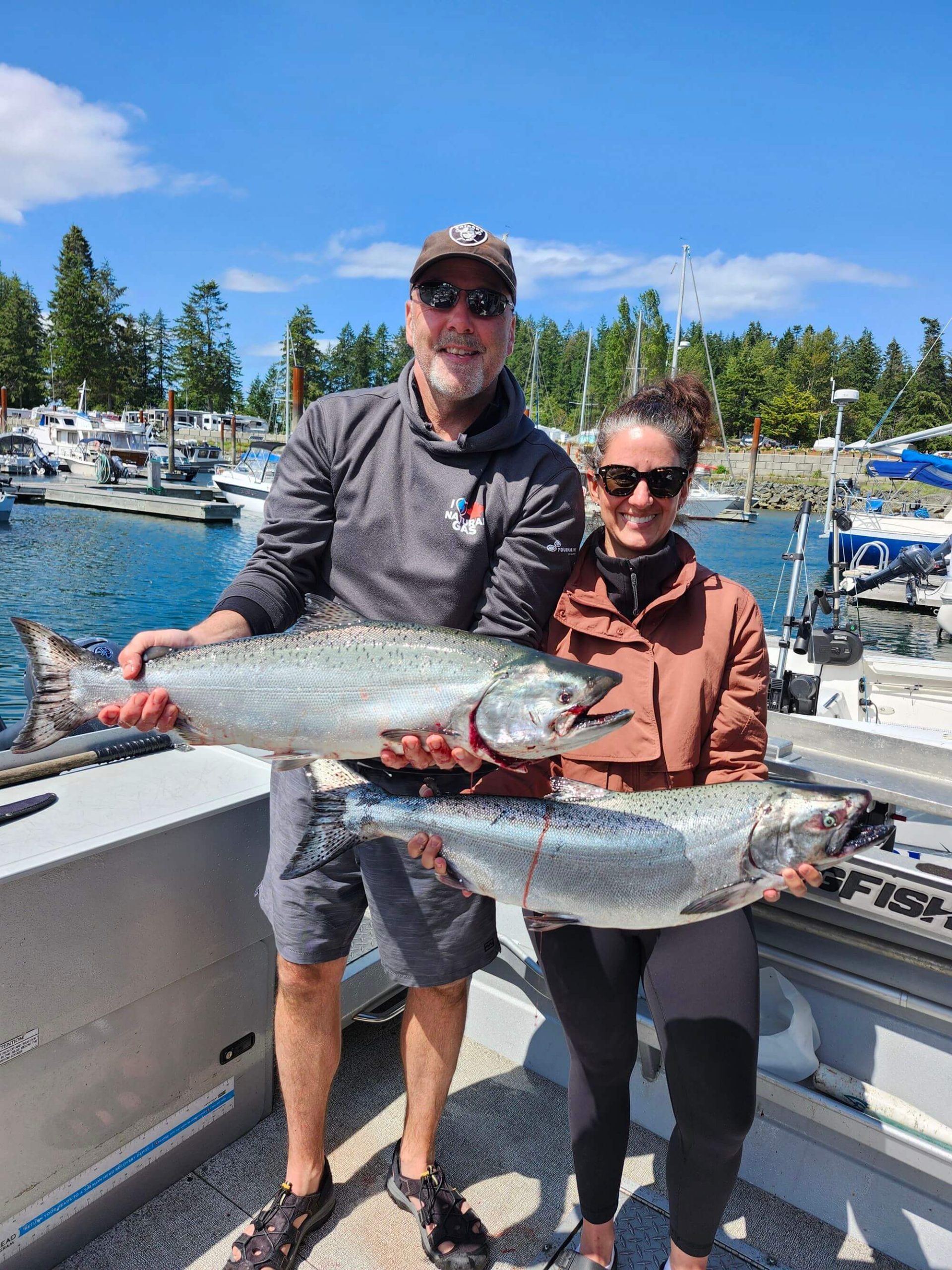 A man and woman both caught large salmons.