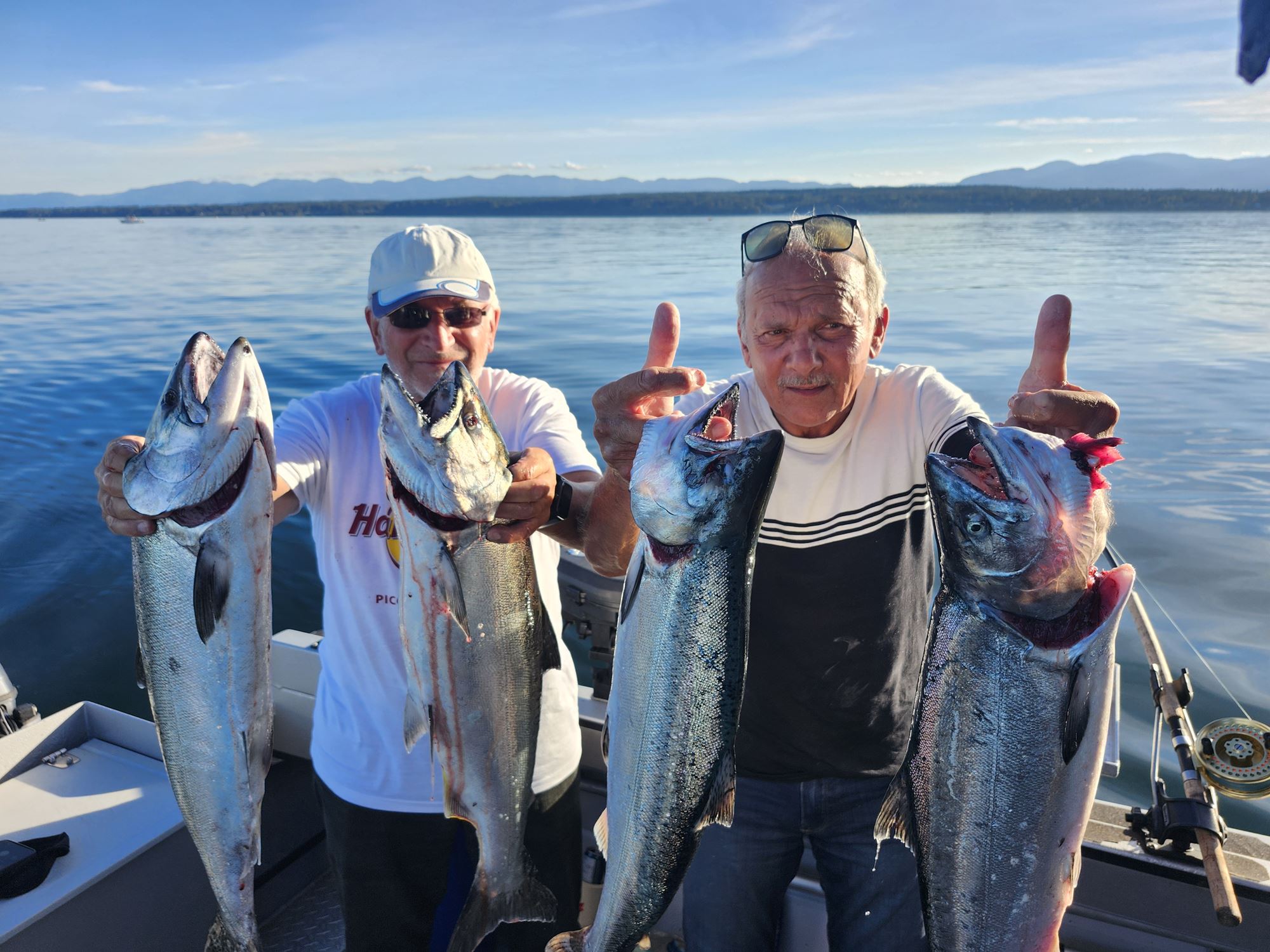 Two men hold up their freshly caught salmon