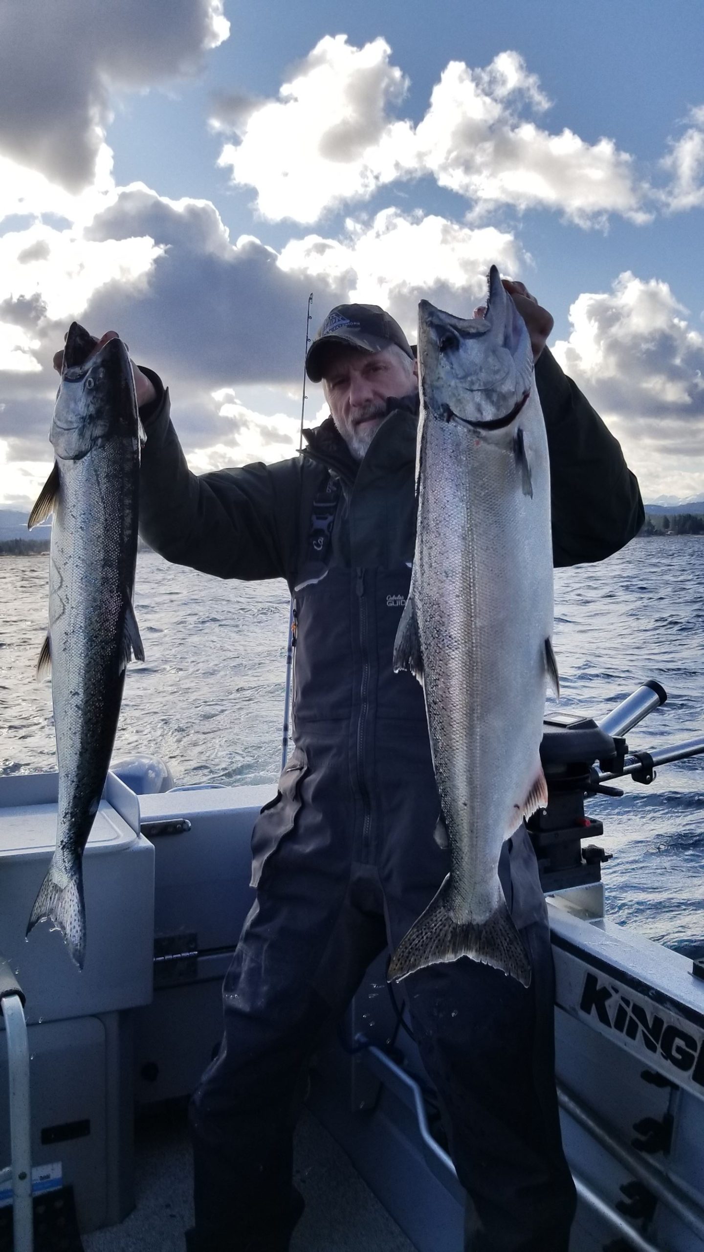 A man holds up two salmon